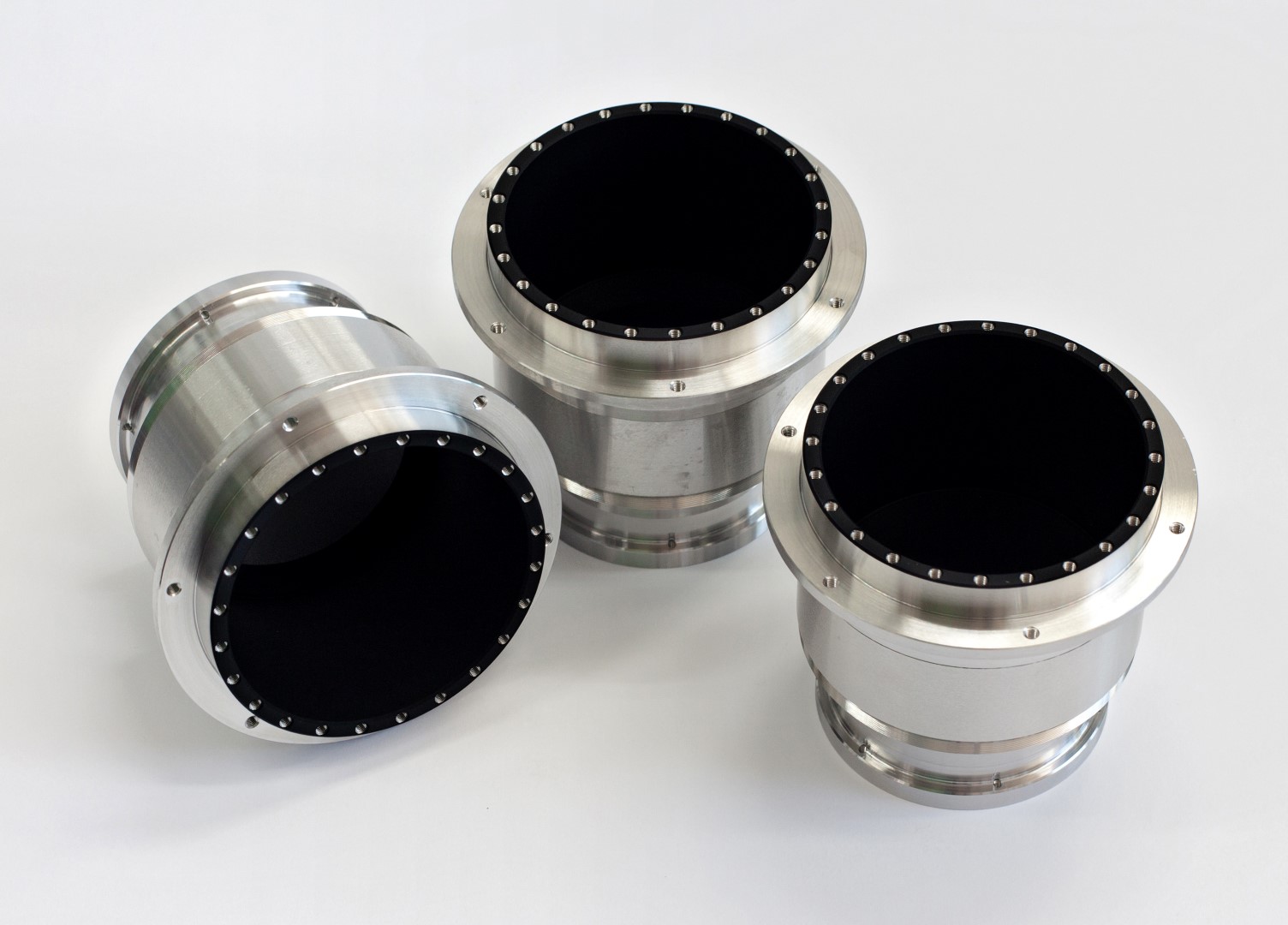 3 circular metallic components coated with acktar's Vacuum Black coating